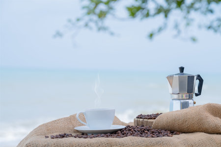 Close-up white coffee cup and many coffee beans placed around on wood table with a beautiful...