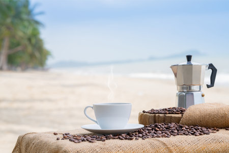 Close-up white coffee cup and many coffee beans placed around on the wood table with a beautiful seascape of nature background, concept coffee vacation travel.の写真素材