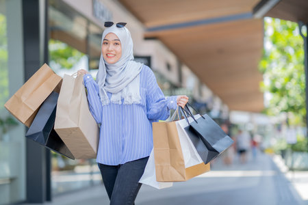 An Asian Muslim woman is carrying a bag of goods that she has been shopping for and buying a lot of products with happy, happy faces.の写真素材