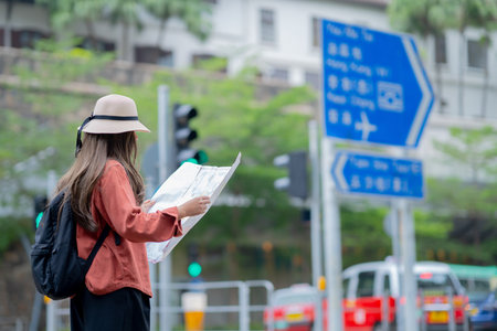 Asian tourist, cute woman with long hair are traveling in Hong Kong along with map and her camera...