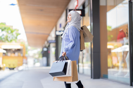 An Asian Muslim woman is carrying a bag of goods that she has been shopping for and buying a lot of products with happy, happy faces.の写真素材