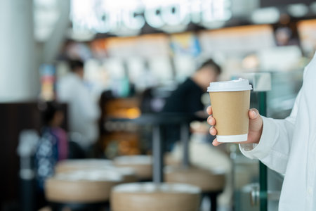 A casual woman standing in front of coffee shop with take away hot coffee cup in hand let caffeine refresh a body before workの写真素材