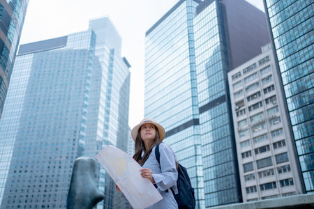 Asian tourist, cute woman with long hair are traveling in Hong Kong along with map and her camera with fun on her holiday,traveler relaxing and enjoying at city and buildingの写真素材