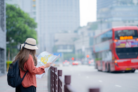 Asian tourist, cute woman with long hair are traveling in Hong Kong along with map and her camera with fun on her holiday,traveler relaxing and enjoying at city and buildingの写真素材