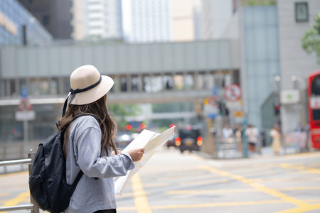 Asian tourist, cute woman with long hair are traveling in Hong Kong along with map and her camera with fun on her holiday,traveler relaxing and enjoying at city and buildingの写真素材