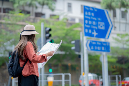 Asian tourist, cute woman with long hair are traveling in Hong Kong along with map and her camera with fun on her holiday,traveler relaxing and enjoying at city and buildingの写真素材