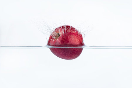 Red apple falling into water with splash isolated on a white background.