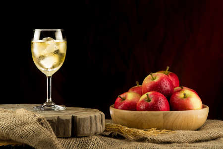 Glass of cider with red apples on a wooden plate and dark backgroundの写真素材