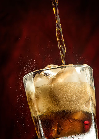 whiskey splashing into a glass with ice on a dark background