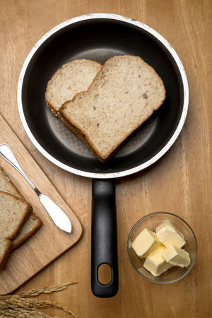 Sliced bread and butter in a frying pan on wooden backgroundの写真素材