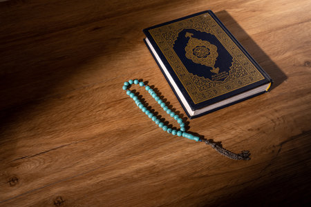 Holy Quran with rosary on wooden background. Ramadan Kareem. Arabic word translation: The Holy Al Quran (holy book of Muslims), on black background, with copy space.の写真素材
