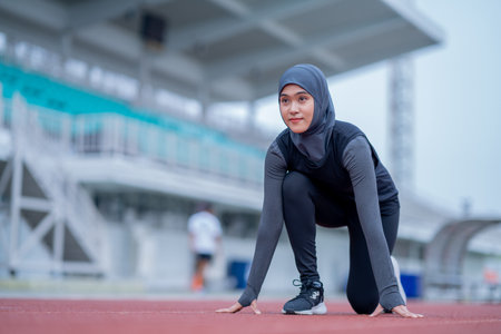 muslim woman in sportswear ready to run at stadium trackの写真素材