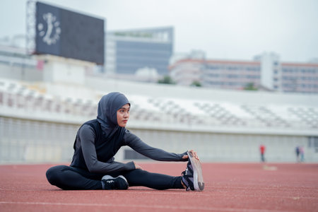 young muslim woman stretching and warming up before running in the stadiumの写真素材