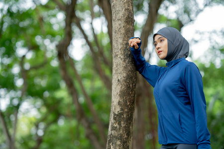 Portrait of a muslim woman drinking water after jogging in the park.の写真素材