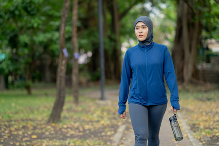Portrait of a muslim woman drinking water after jogging in the park.の写真素材