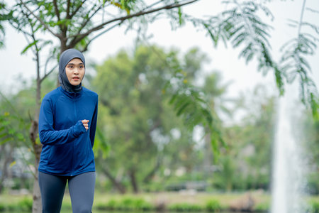 Asian cute muslim woman wearing sportswear and a blue hijab Exercising and running outdoors at the park in the morning. with a fresh feeling.の写真素材