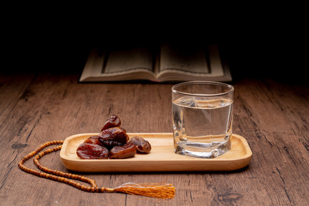Many Date Palms are on bowls and cups of water and the Quran is on wooden tables, to wait for the time of Iftar, with the concept of ramadan Muslims around the world.の写真素材