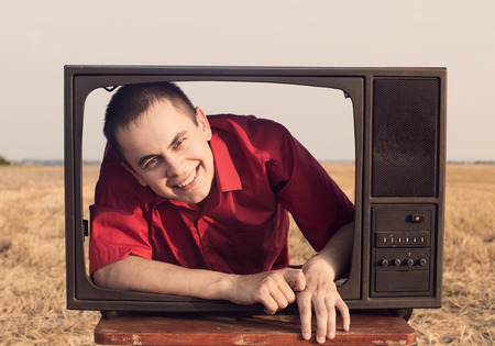 young men with TV in summer fieldの写真素材