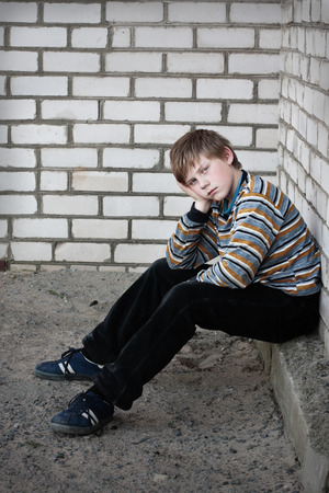 sad boy on background wallの写真素材