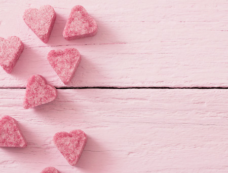 Granulated pink sugar  in the shape of heart on a wooden backgroundの写真素材