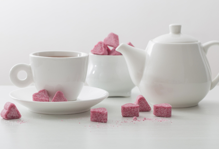 Granulated pink sugar  in the shape of heart and cup of tea  on white backgroundの写真素材