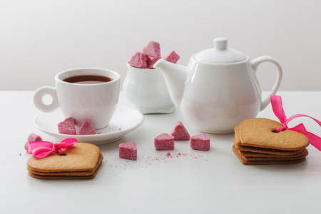 Granulated pink sugar  in the shape of heart and cup of tea  on white backgroundの写真素材
