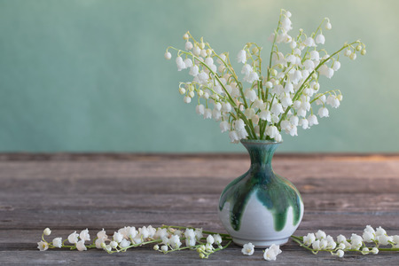 Lilly of valley in vase on wooden tableの写真素材