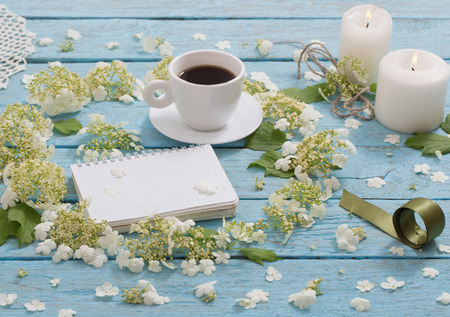 beautiful composition with a cup of coffee and white flowers on a blue wooden backgroundの写真素材