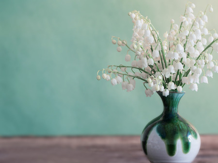 Lilly of valley in  vase on wooden tableの写真素材
