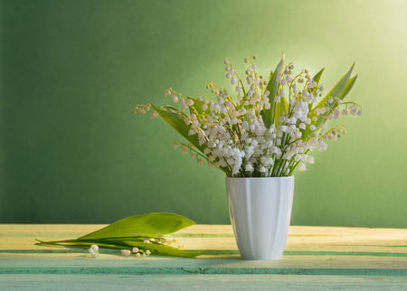 Lilly of valley in  vase on green backgroundの写真素材