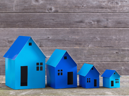 A paper houses stands over a wooden backgroundの写真素材