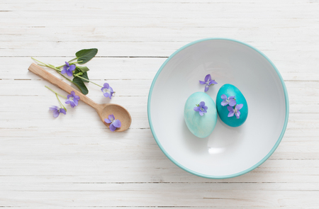 aster eggs with flowers on white wooden tableの写真素材