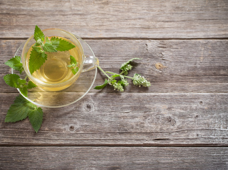 green melissa herbal tea in glass cup on wooden backgroundの写真素材