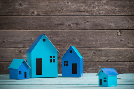 A paper houses stands over a wooden backgroundの写真素材