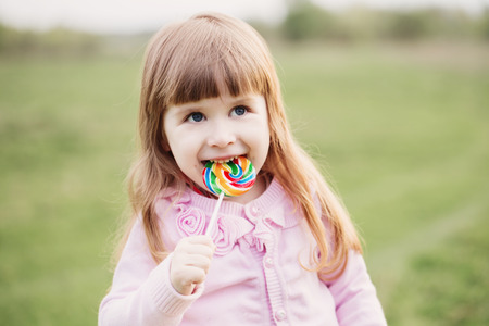 little girl holding lollipop in her handの写真素材