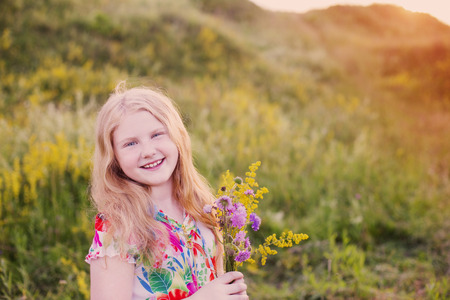happy blond girl on meadow at sunsetの写真素材