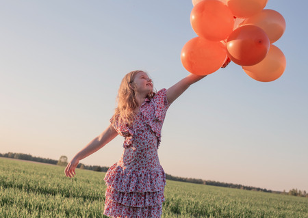happy girl with orange balloons outdoorの写真素材