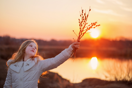 blond girl with willow on sunsetの写真素材