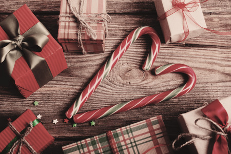 candy canes as heart and gifts on wooden boardの写真素材
