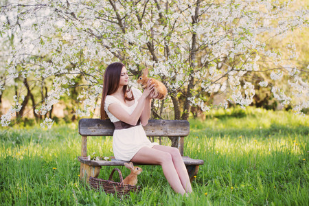 beautiful young woman with rabbits in gardenの写真素材
