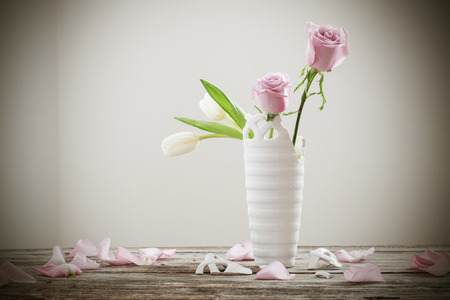 pink roses in broken flower vase on old wooden tableの写真素材