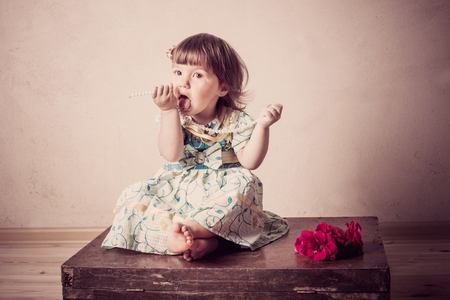 little girl sits on an old suitcaseの写真素材
