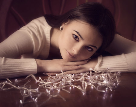 beautiful woman sitting at table with Christmas light garland