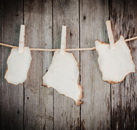 old burnt paper attach to rope with clothes pins on wooden backgroundの写真素材