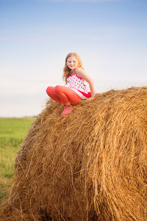 girl on the straw after harvest fieldの写真素材