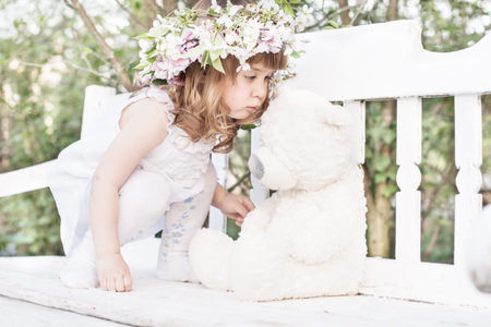 little girl with toy on white wooden benchの写真素材