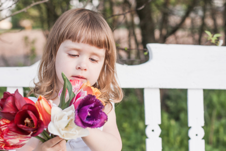 happy girl with tulips on white wooden benchの写真素材