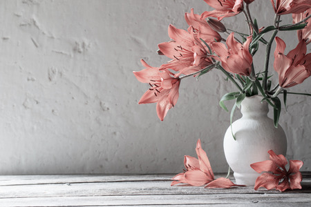 orange lily in vase on wooden tableの写真素材