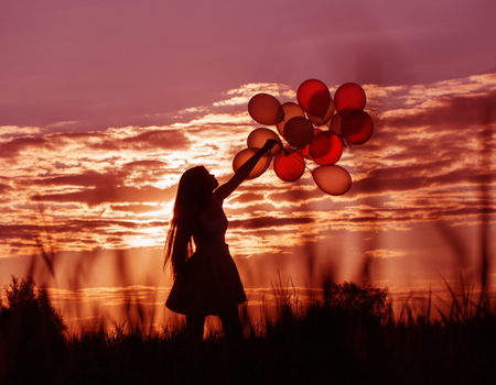 young women with balloons at sunsetの写真素材