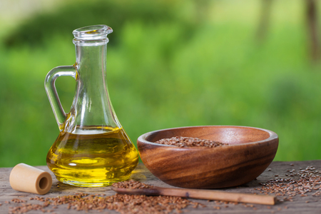 flax seeds and linseed oil in a glass jug on a wooden tableの写真素材